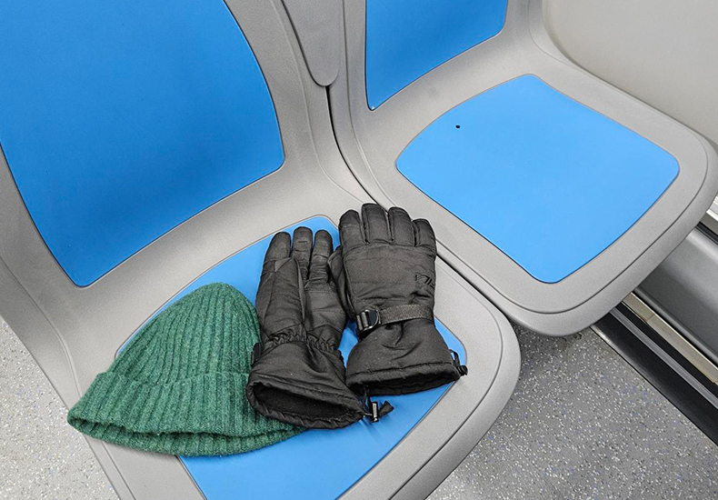 Green toque and winter gloves left on a bus seat.